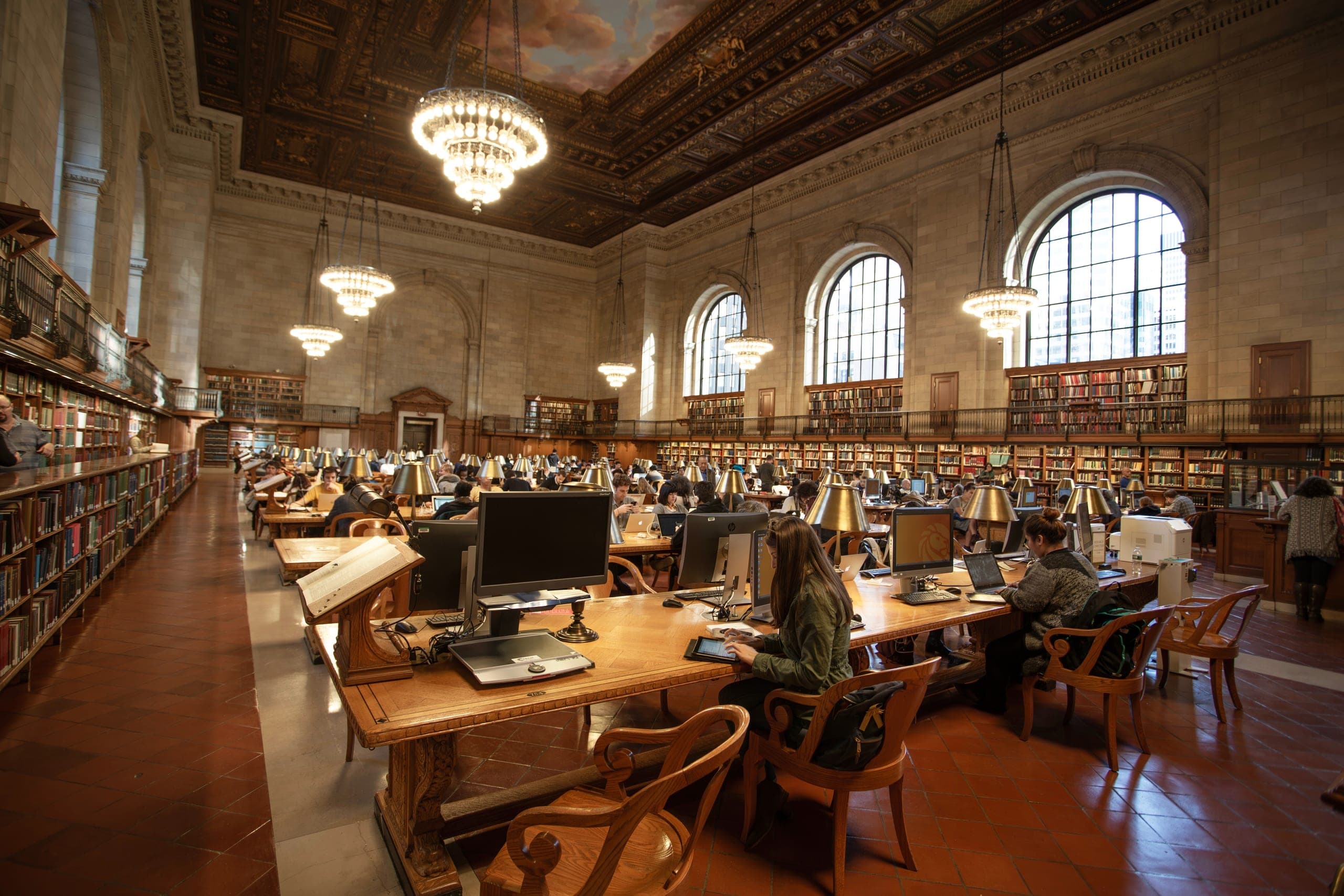 Public library users working on computers and tablets in the interior of New York public library in New York. 
