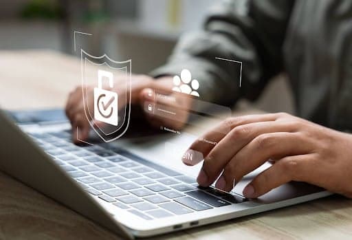 A person typing on a laptop secured with a shield, illustrating how to protect Fastvue Reporter.