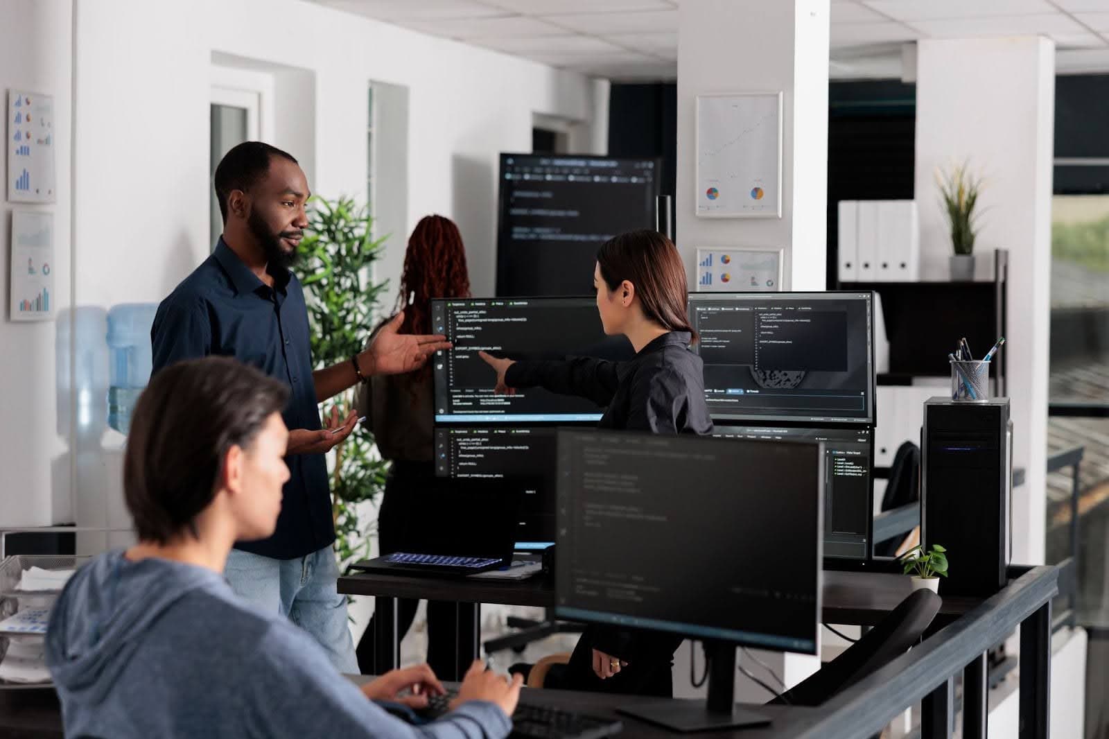 Two individuals focused on their computers while collaborating in a modern office environment.