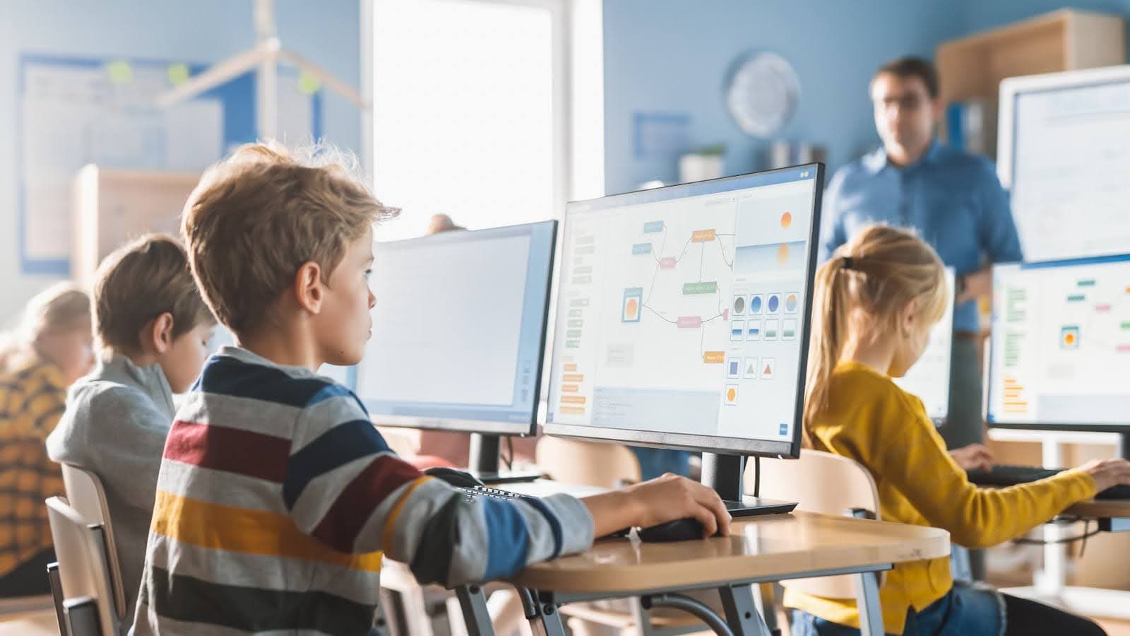 Children in the classroom engaging in online learning at desktop computers